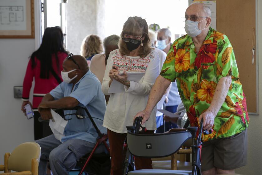 Lakewood, CA - March 31: Jack Orre, 89, and his daughter Linda Davis, 60, wait in line for coronavirus vaccine at a COVID-19 vaccine clinic help by L.A. County Department of Public Health for seniors at Whispering Fountains Senior Living Community on Wednesday, March 31, 2021 in Lakewood, CA.(Irfan Khan / Los Angeles Times)