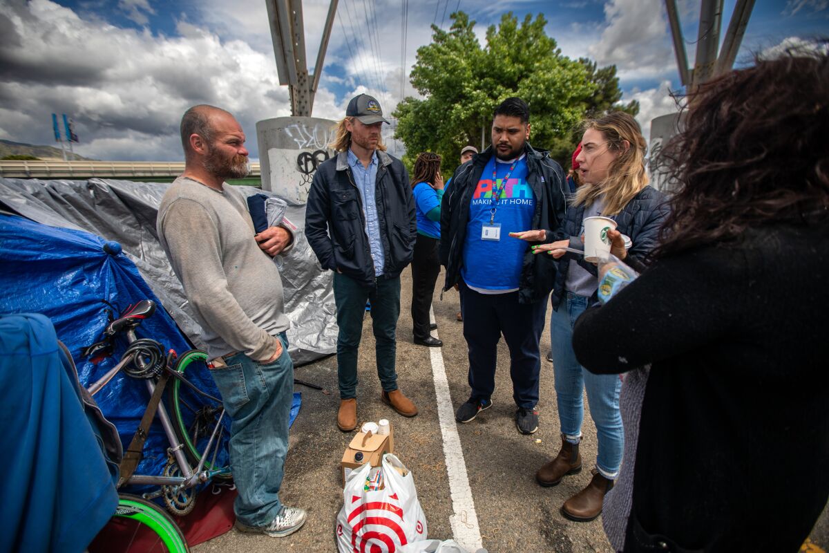 A group of service workers talk with an unhoused man