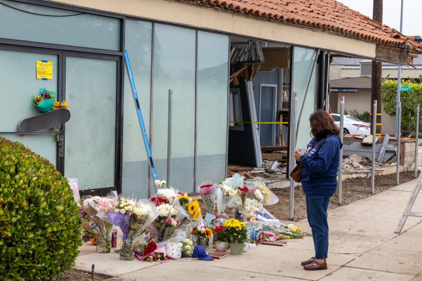 Pasadena, CA - May 14: A person who didn't want to give their name pays their respects at a memorial where three people died and three were severely injured after their Tesla crashed into a building while traveling at speeds of over 100 mph in on E. Foothill Blvd. in Pasadena Tuesday, May 14, 2024. (Allen J. Schaben / Los Angeles Times)