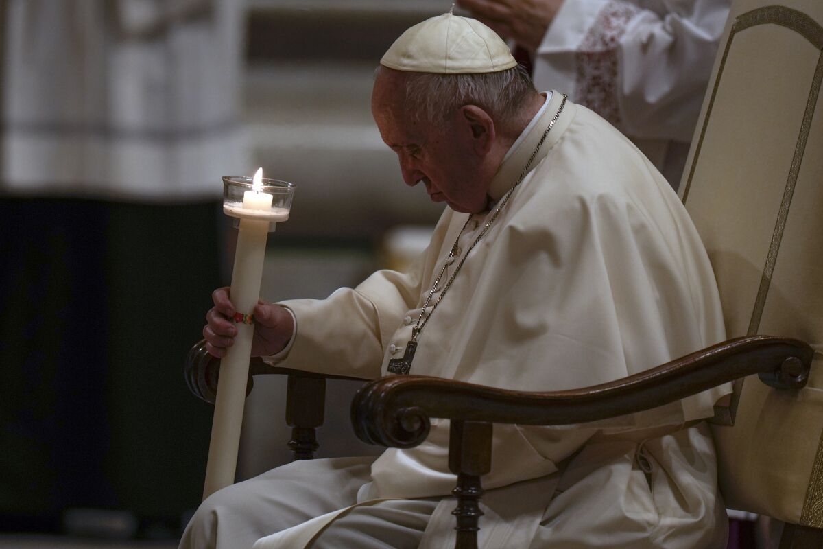Pope Francis holds a Paschal candle as he presides over a Easter vigil ceremony at St. Peter's Basilica at the Vatican, Saturday, April 16, 2022. (AP Photo/Alessandra Tarantino)