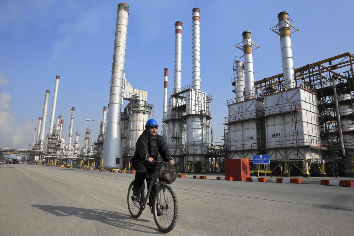 An oil worker rides a bicycle at an Iranian refinery south of Tehran in December 2014. Because of last year’s nuclear agreement with the Obama administration and other countries, Iran is producing more oil for the global market, putting downward pressure on prices.