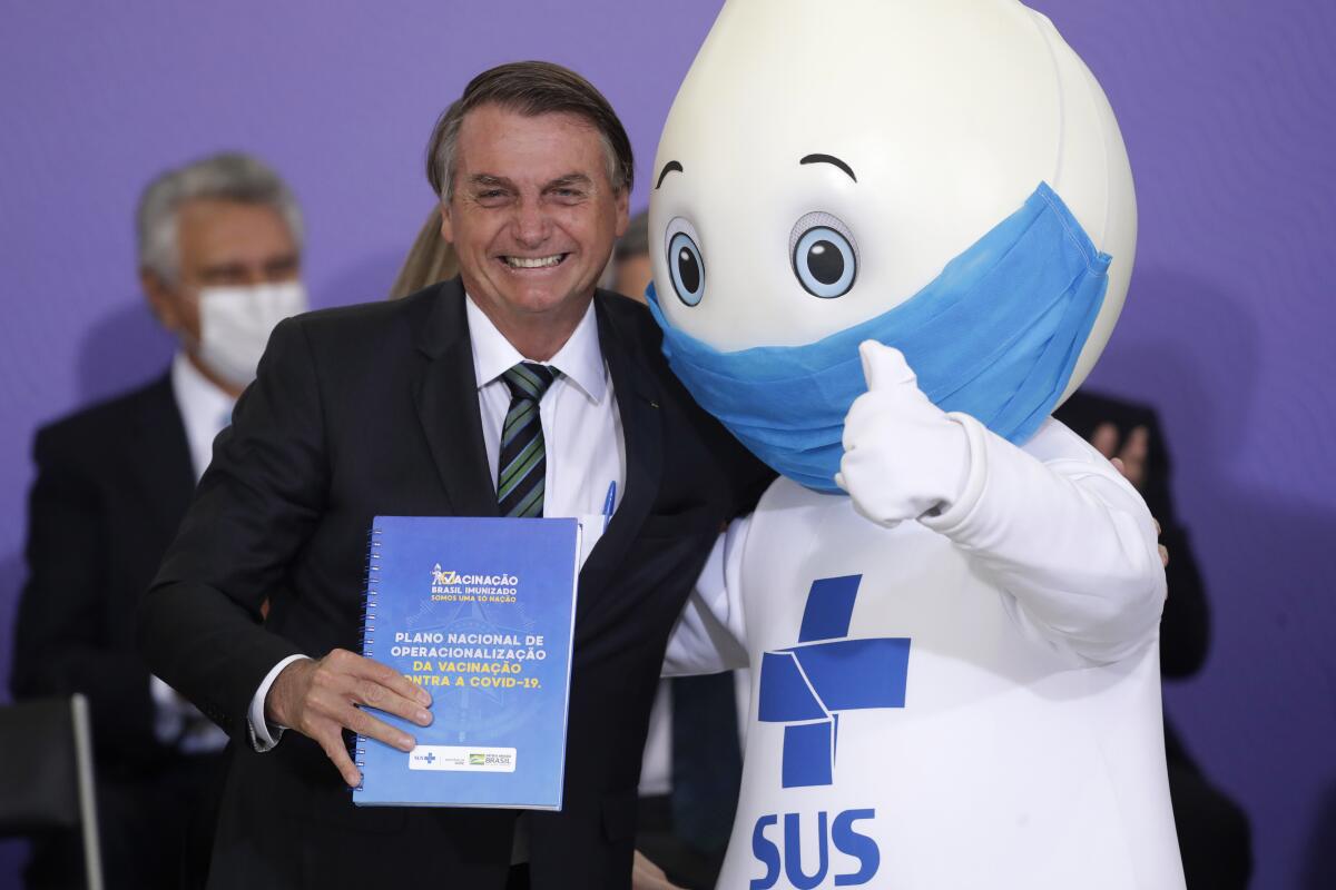 Brazilian President Jair Bolsonaro poses with the mascot of the nation's vaccination campaign.