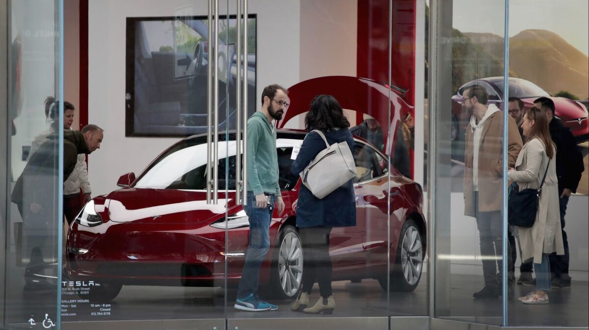 Visitors check out a Model 3 on display at a Tesla retail store in Chicago.