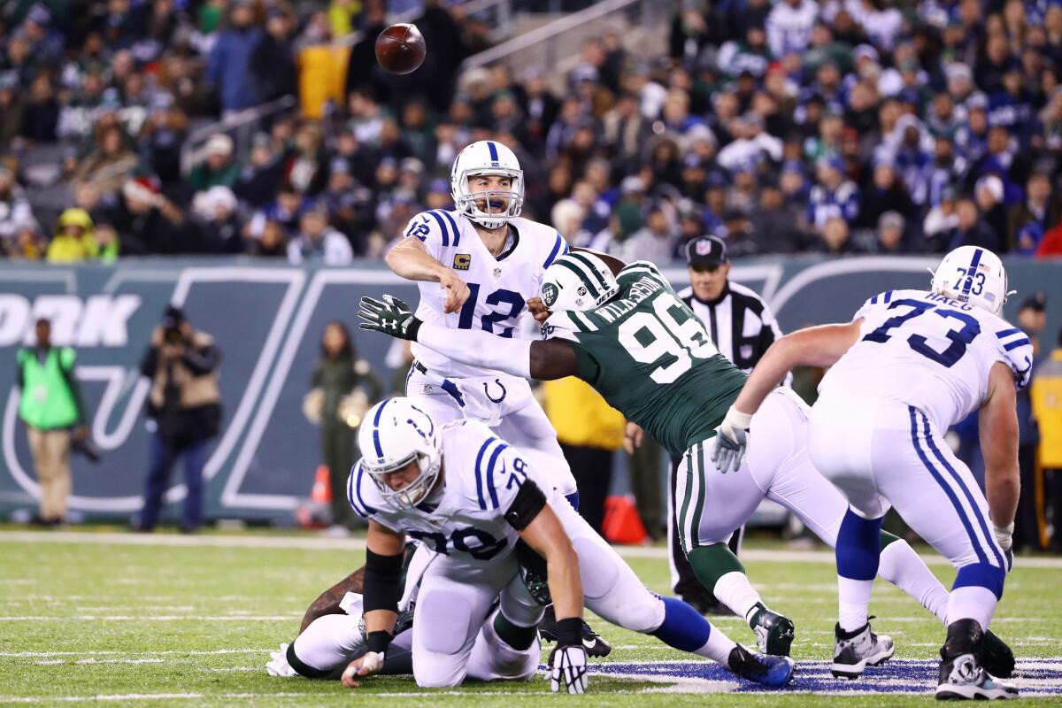 EAST RUTHERFORD, NJ - DECEMBER 05: Andrew Luck #12 of the Indianapolis Colts passes under pressure from Muhammad Wilkerson #96 of the New York Jets in the first half during their game at MetLife Stadium on December 5, 2016 in East Rutherford, New Jersey.