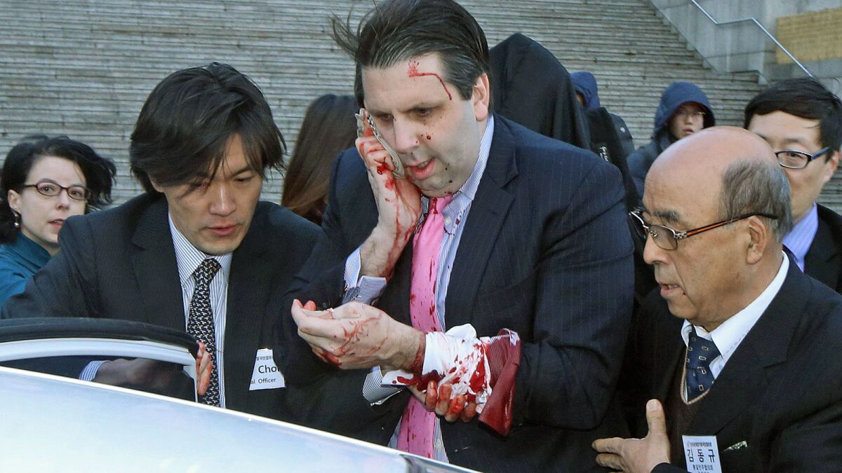 U.S. Ambassador to South Korea Mark Lippert is escorted into a car to head to a hospital after he was attacked in Seoul.
