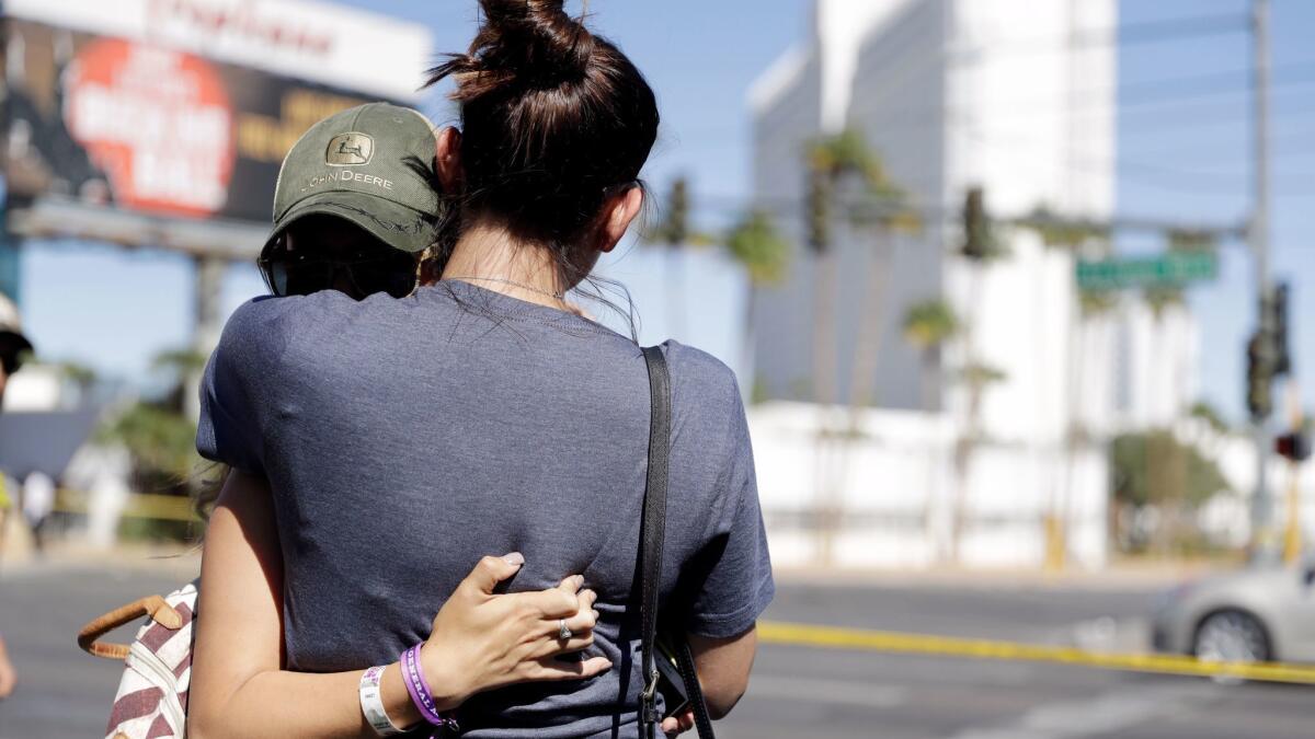 Aria James, her back to the camera, and Jenna Kerr, from Ventura, embrace Monday on the Las Vegas Strip near a concert venue where a mass shooting occurred. Both attended the concert.