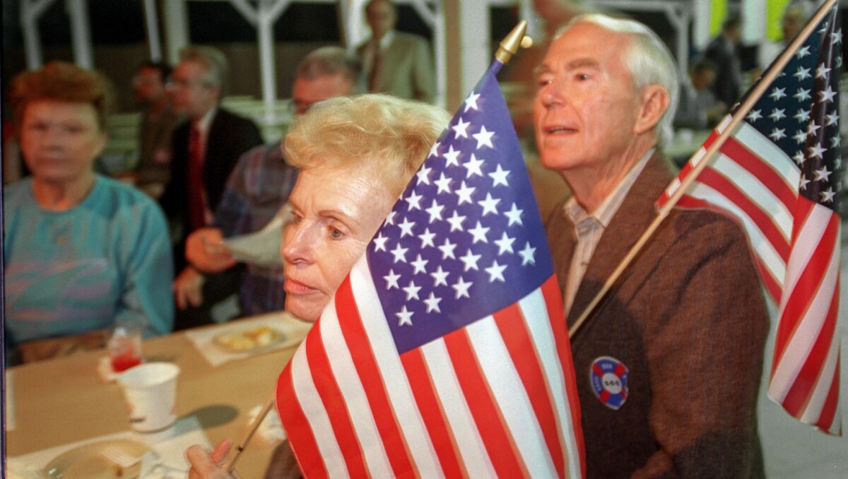 Tom y Martha Lang de Laguna Niguel ondean banderas americanas y muestran su apoyo a la Proposición 187