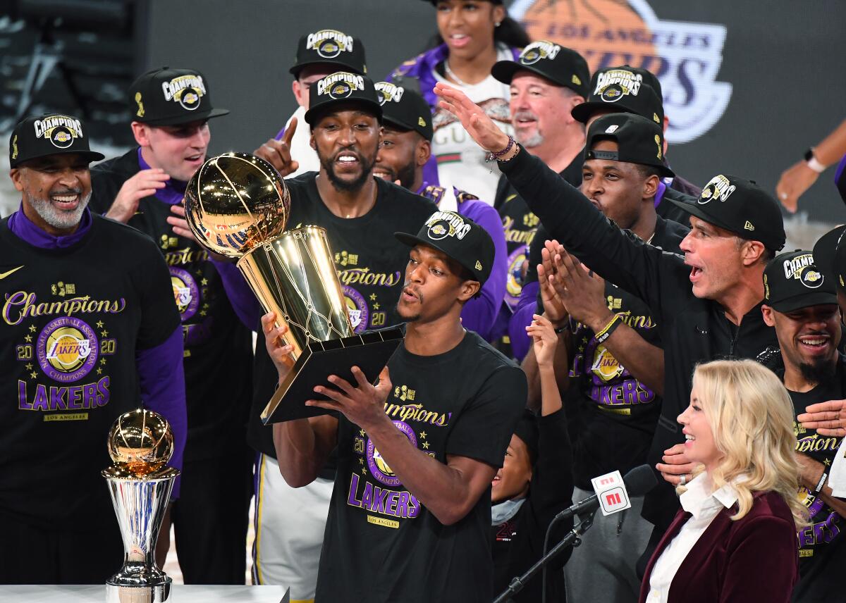Lakers guard Rajon Rondo holds the Larry O'Brien trophy in front of his teammates and Lakers owner Jeanie Buss.