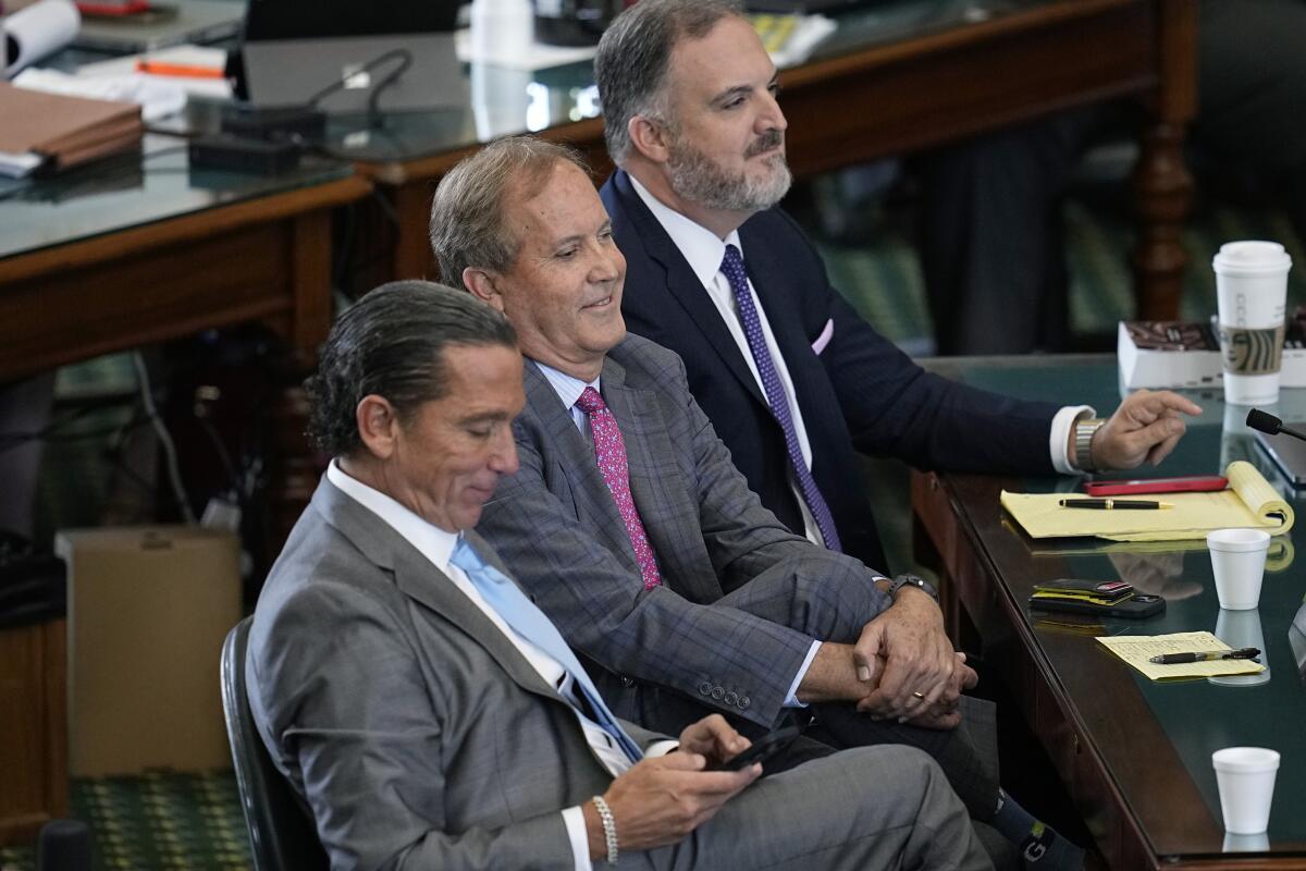 Texas state Atty. Gen. Ken Paxton sits between two attorneys in the Senate Chamber at the Texas Capitol.