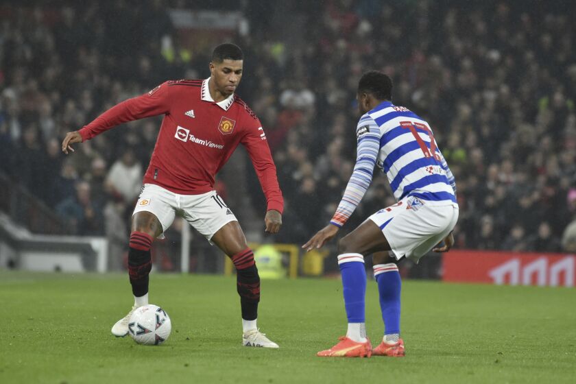 Manchester United's Marcus Rashford, left, defends the ball from Reading's Baba Rahman during the English FA Cup 4th round soccer match between Manchester United and Reading at Old Trafford in Manchester, England, Saturday, Jan. 28, 2023. (AP Photo/Rui Vieira)