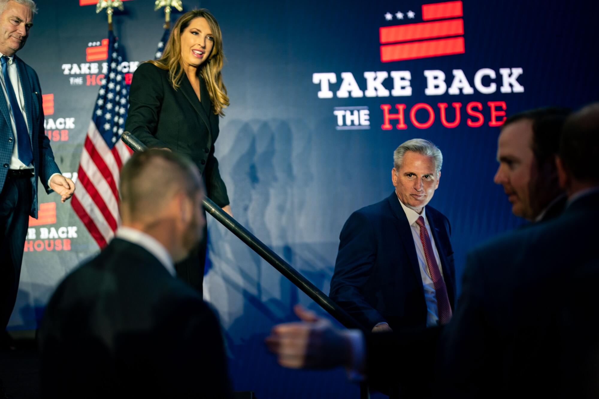 「Take Back the House」と書かれたロゴの近くで、他の人々に混じって階段を降りる男性。