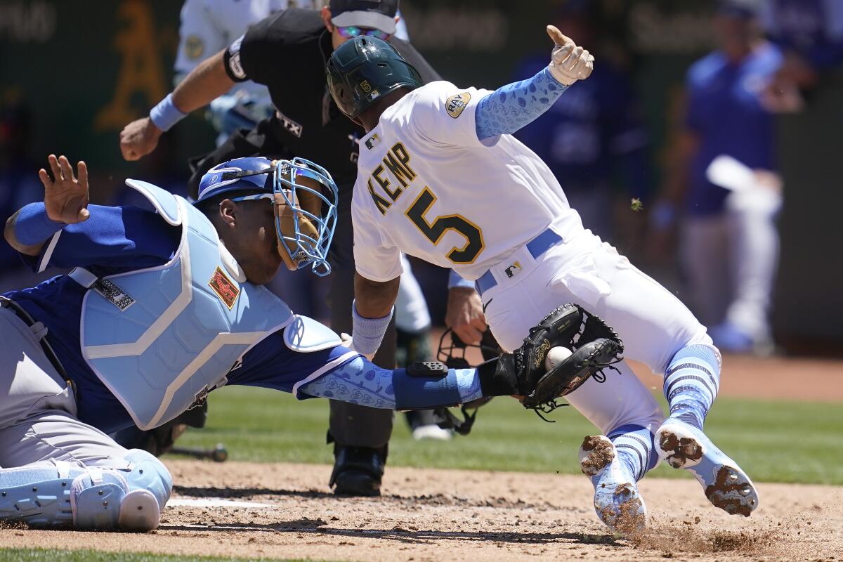 Kansas City Royals catcher Salvador Perez, left, tags out Oakland Athletics' Tony Kemp (5) at home during the third inning of a baseball game in Oakland, Calif., Sunday, June 19, 2022. (AP Photo/Jeff Chiu)