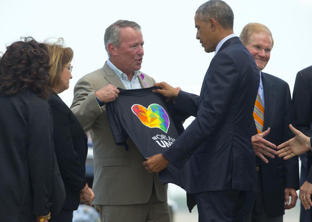 President Obama looks at a T-shirt being presented to him by Orlando, Fla., Mayor Buddy Dyer.