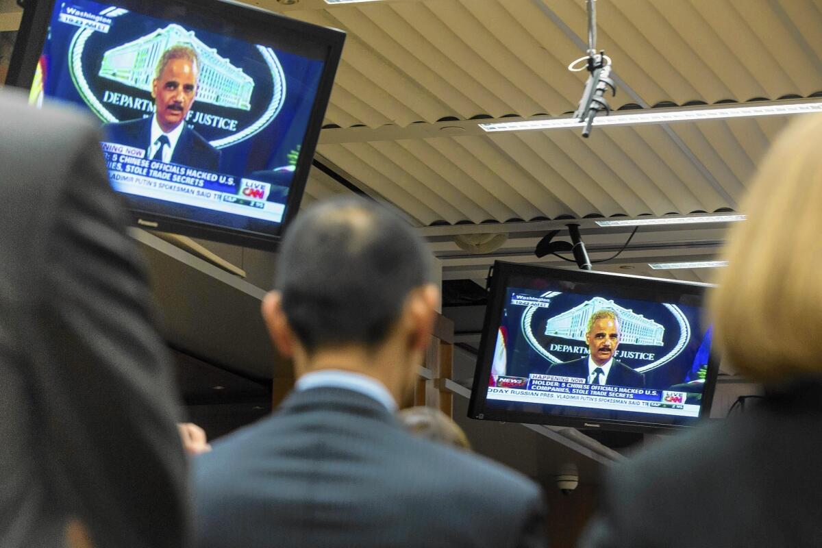 Justice Department staff members watch as Atty. Gen. Eric H. Holder Jr. announces the federal indictment of five Chinese military officials for allegedly stealing U.S. corporate trade secrets.