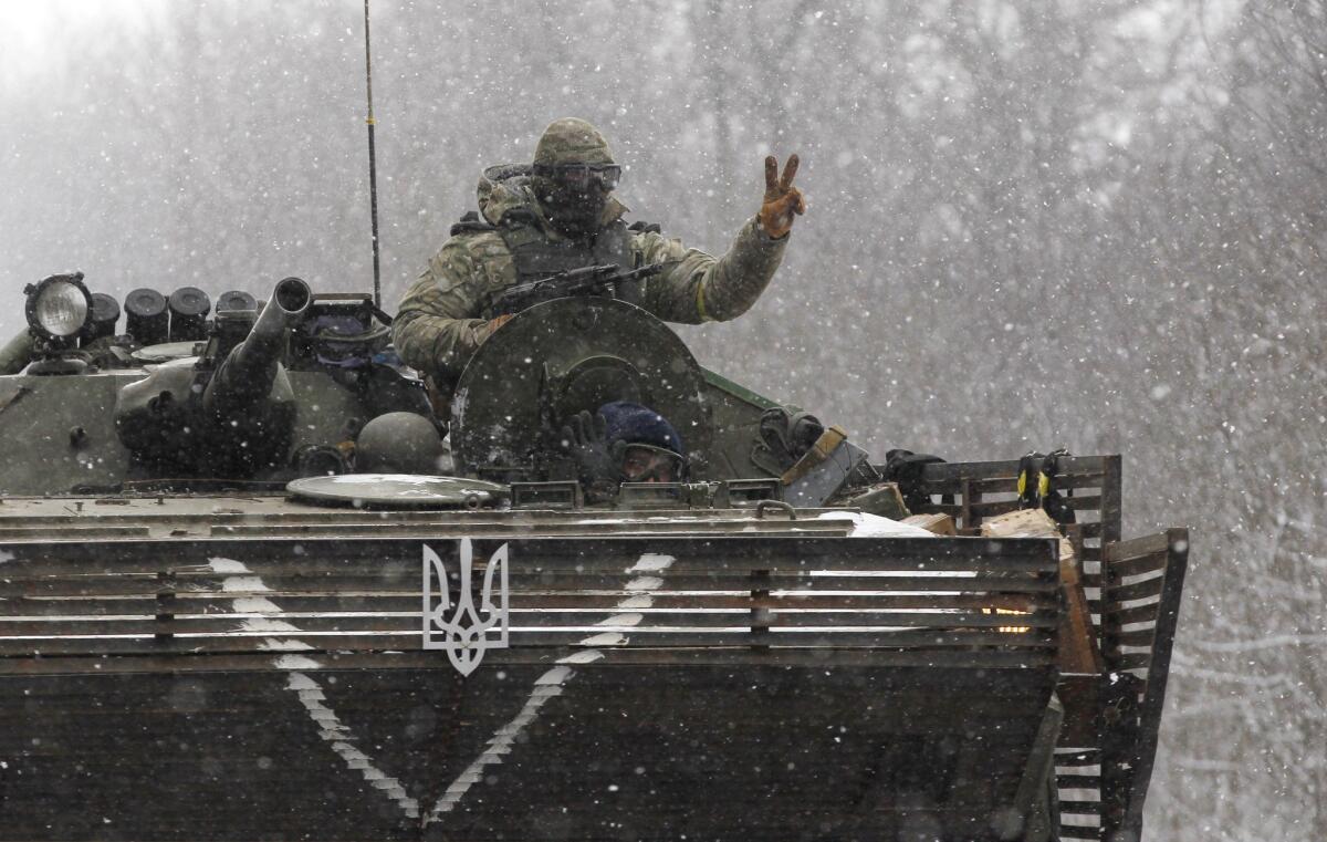 A Ukrainian soldier flashes a victory sign while driving his armored vehicle on a road near Debaltseve, in eastern Ukraine, on Monday. Fighting over Debaltseve has continued despite a cease-fire that began Sunday.