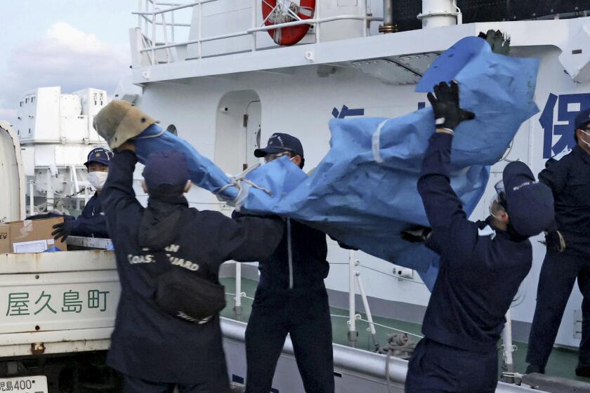The members of Japanese Coast Guard carry the debris which are believed to be from the crashed U.S. military Osprey aircraft, at a port in Yakushima, Kagoshima prefecture, southern Japan, Monday, Dec. 4, 2023. Japanese and American military divers have spotted what could be the remains of a U.S. Air Force Osprey aircraft that crashed last week off southwestern Japan and several of the six crewmembers who are still missing, local media reported Monday.(Kyodo News via AP)