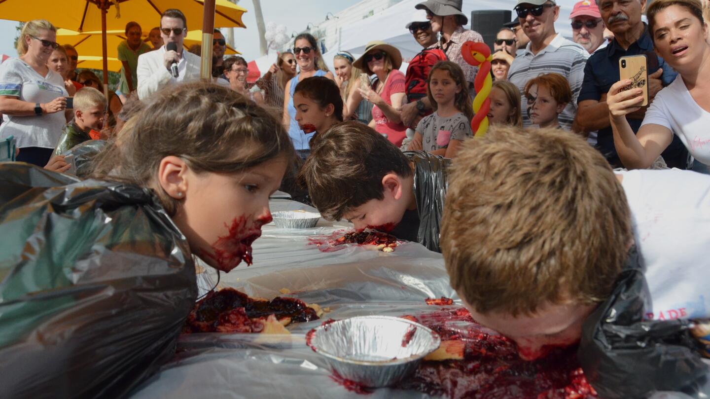 Children dive into boysenberry pies during a pie eating contest at the Balboa Island Carnival & Taste of the Island on Sunday.