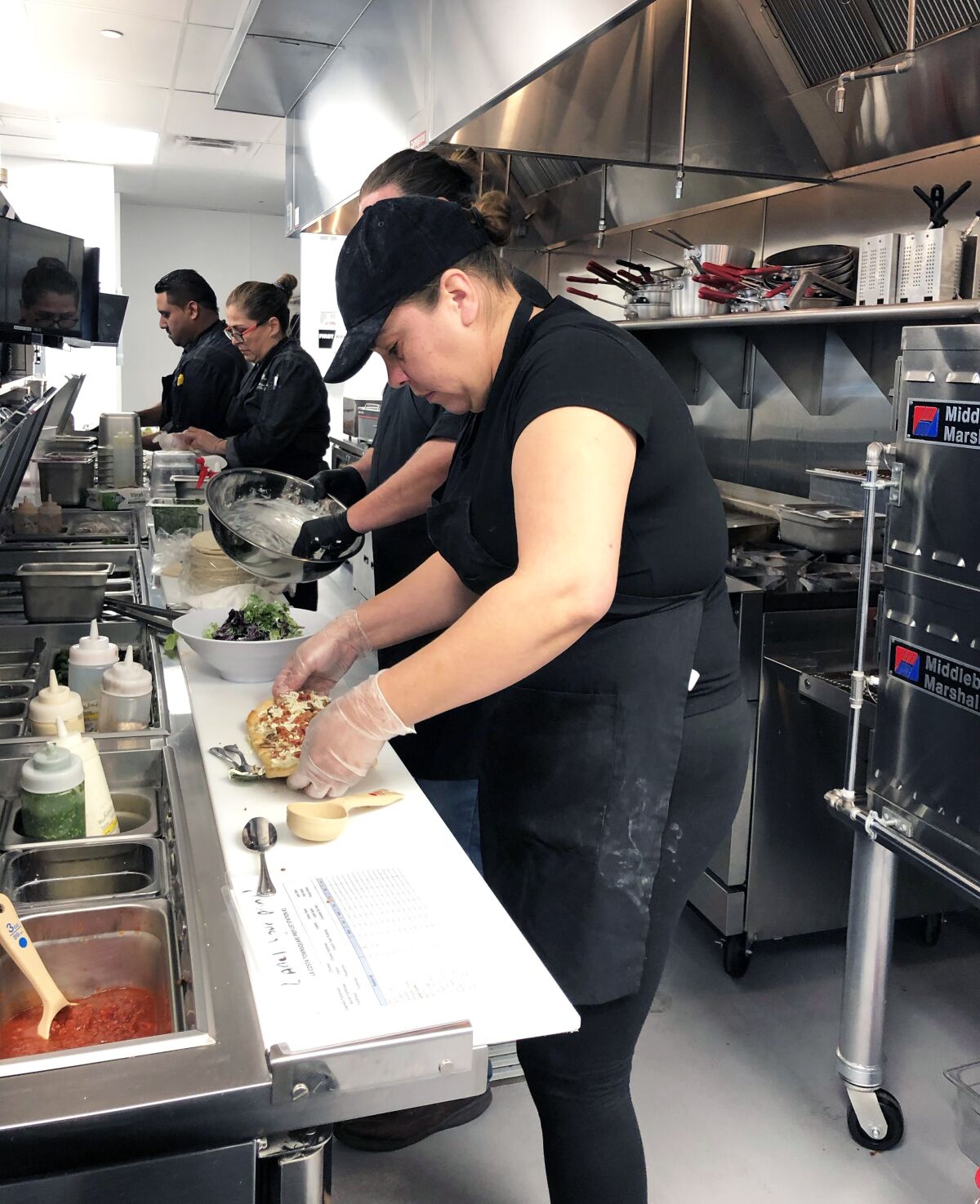 Kitchen staff at Cinépolis Luxury Cinemas La Costa Town Square make pizzas, salads and tacos from scratch on Wednesday, in training for the theater's opening on Feb. 7.