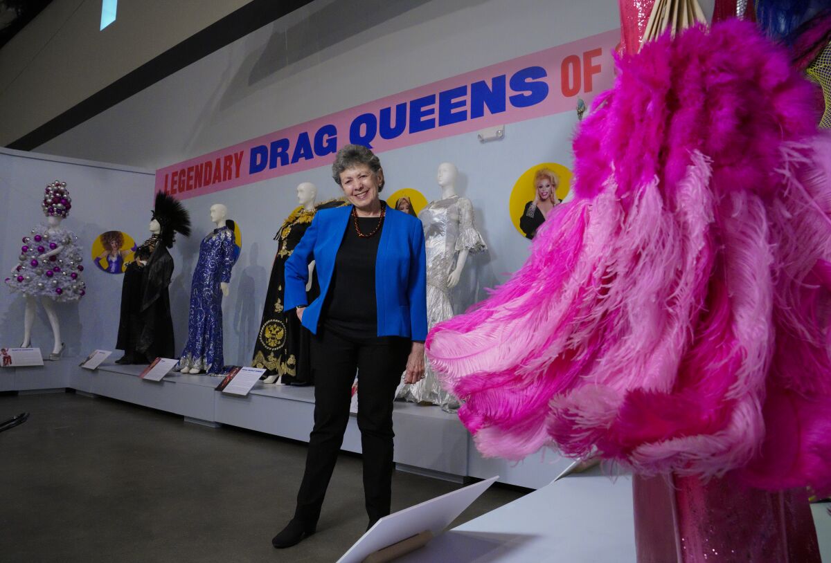Curator Lillian Faderman stands among the costumed mannequins featured in the "Legendary Drag Queens of San Diego" exhibit at the San Diego History Center.
