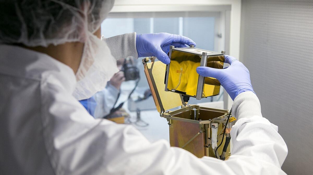 Vidur Kaushish, a mission manager at Tyvak Nano-Satellite Systems, Inc., places a CubeSat, or nano-satellite, into a dispenser on July 26.