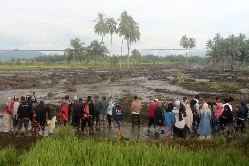 People inspect an area affected by the flash flood that killed a number of people in Agam, West Sumatra, Indonesia, Sunday, May 12, 2024. Heavy rains and torrents of cold lava and mud sliding down a volcano on Indonesia's Sumatra island have triggered flash floods that killed more than a dozen of people and injured others, officials said Sunday. (AP Photo/Ali Nayaka)