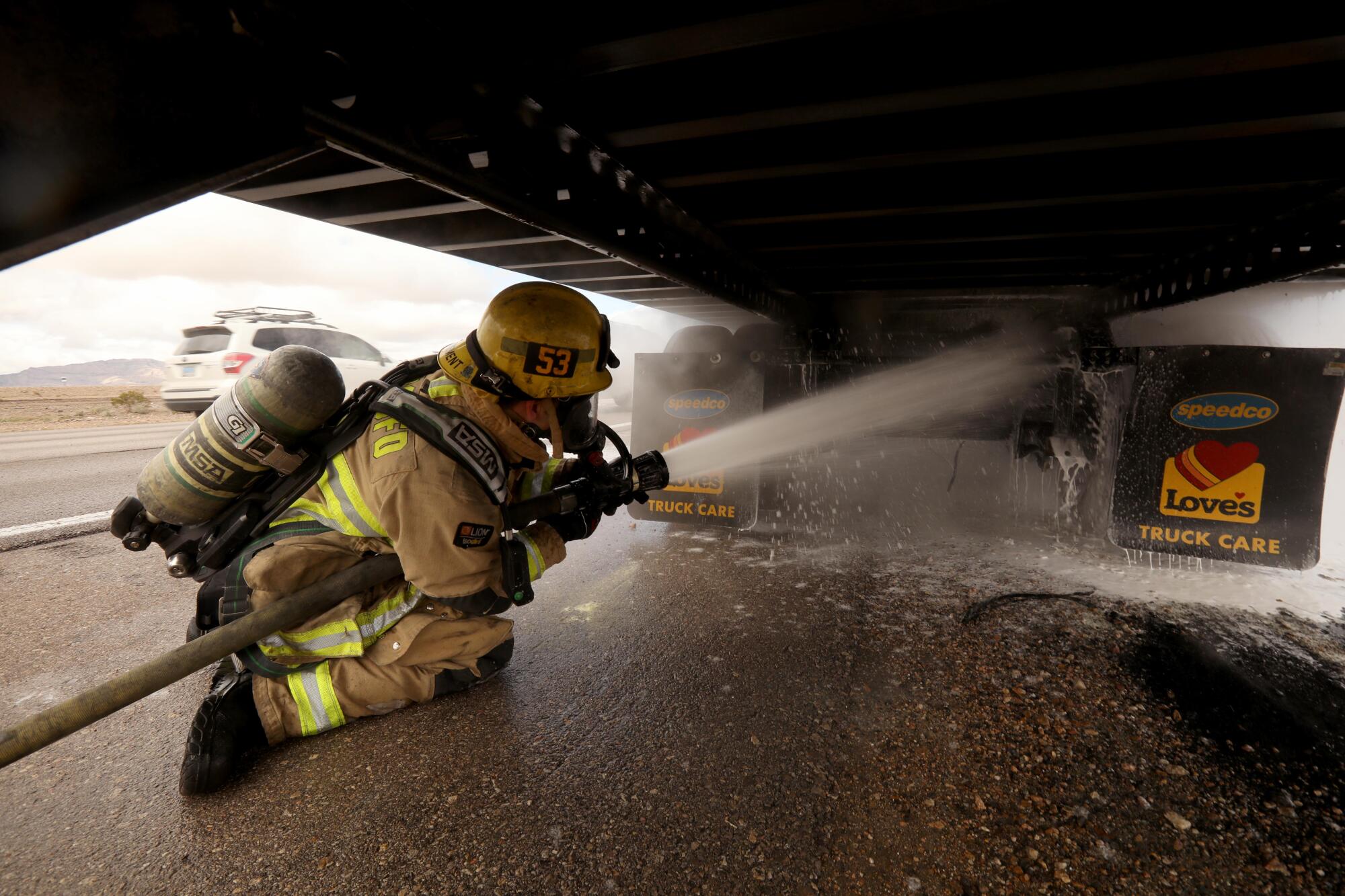 A firefighter cools off the overheated brakes on a truck to prevent it from catching fire just south of Primm, Nevada.