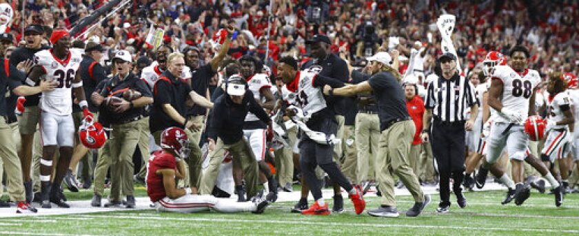 Georgia head coach Kirby Smart offers Alabama quarterback Bryce Young a hand after Georgia defensive back Kelee Ringo intercepted Young and returned it for a touchdown for a 33-18 lead over Alabama late in the second half of the College Football Playoff championship football game Monday, Jan. 10, 2022, in Indianapolis. (Curtis Compton/Atlanta Journal-Constitution via AP)