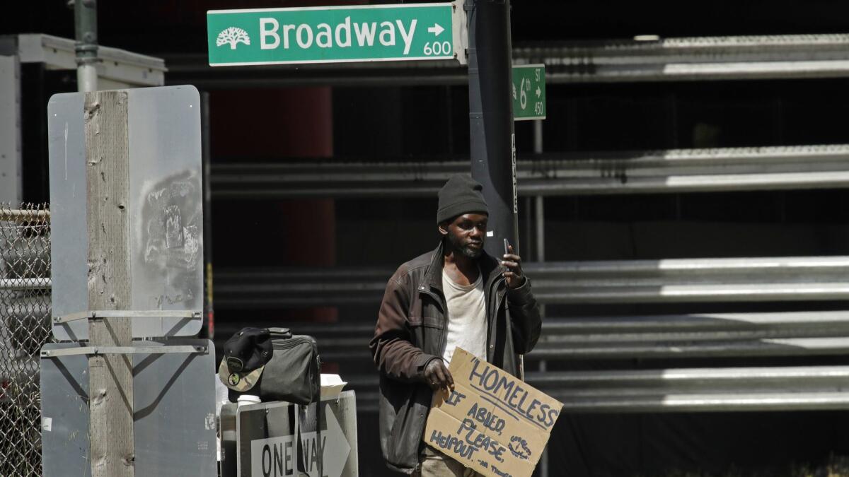 A man waits to panhandle drivers at a traffic signal in Oakland on Friday. California Gov. Gavin Newsom named L.A. County Supervisor Mark Ridley-Thomas as co-chair of a homelessness task force.