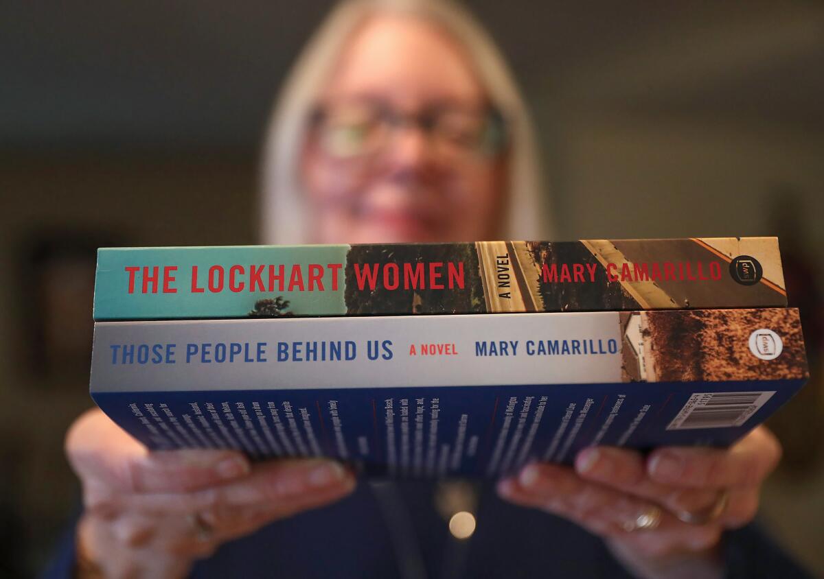 Author Mary Camarillo holds out two of her novels at her Huntington Beach home.
