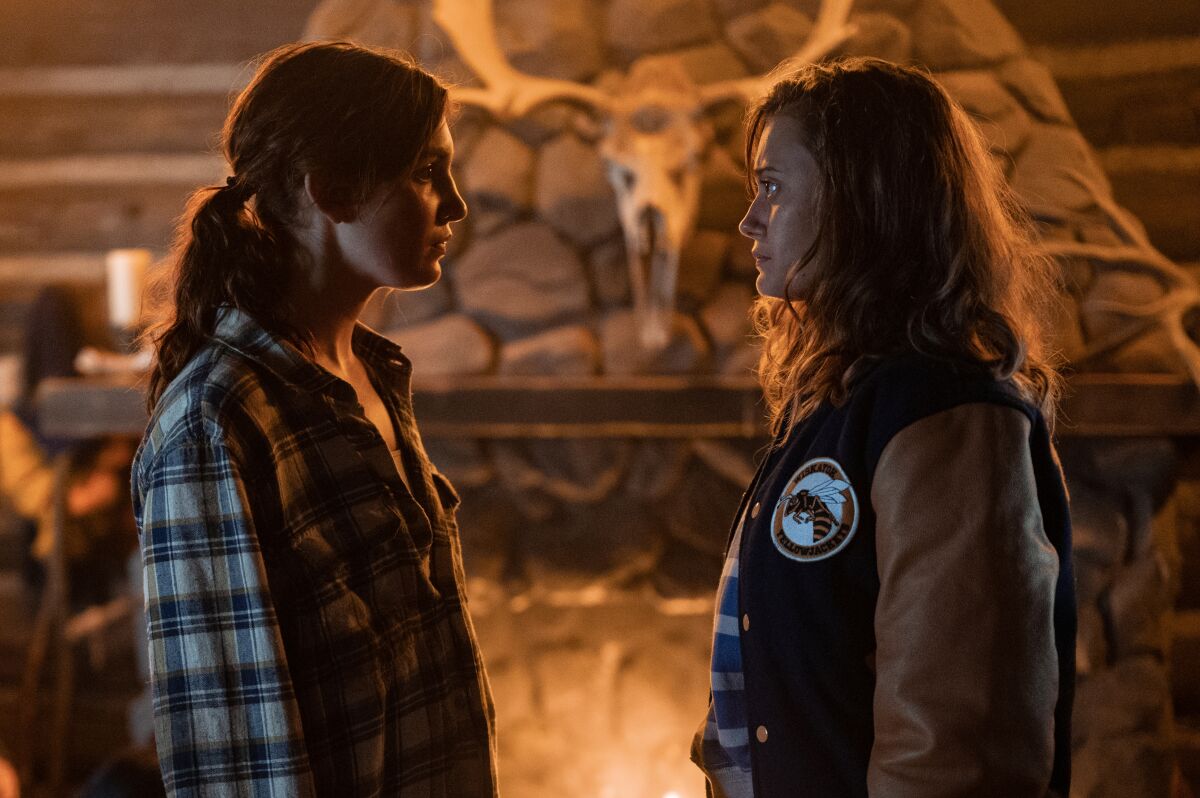Two teen girls face off by firelight in a cabin