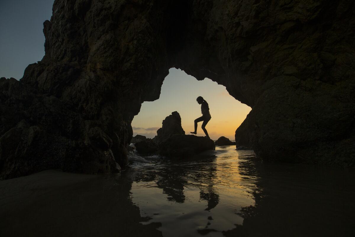 A child walks on a rock formation at the beach