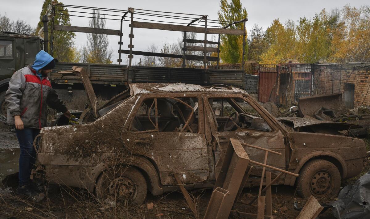 Man next to husk of war-destroyed car