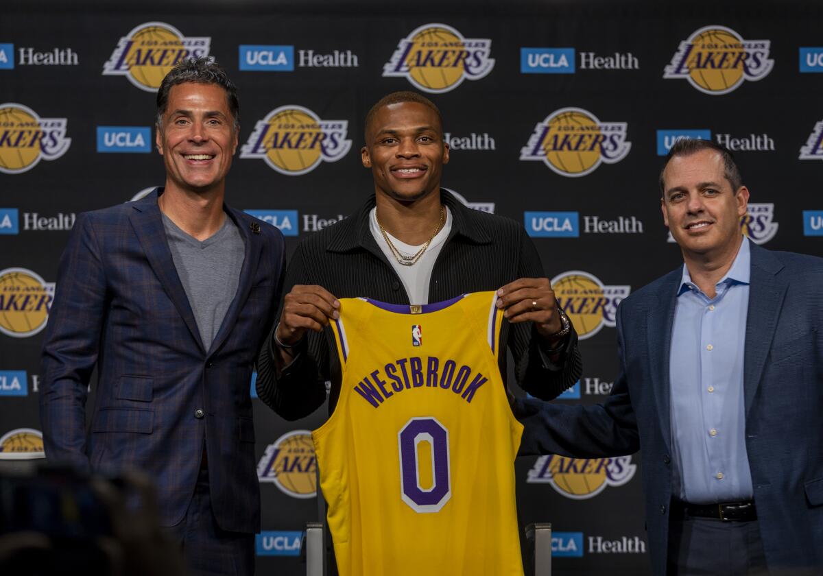Russell Westbrook holds up his Lakers jersey while flanked by Rob Pelinka. left, and Frank Vogel, right.