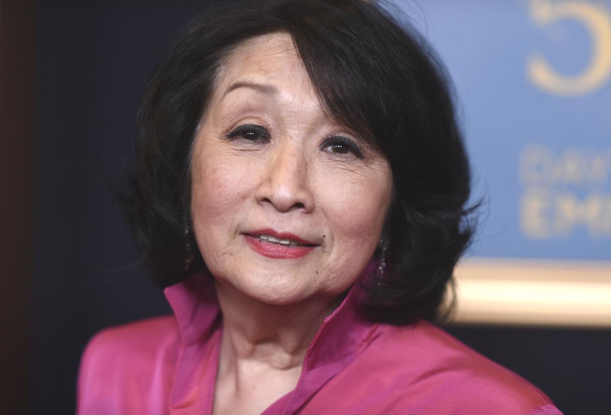 Connie Chung in a pink blouse angling her head as she poses for a photo