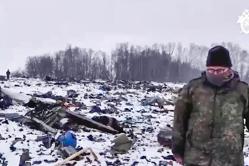 In this photo taken from video released by Russian Investigative Committee on Friday, Jan. 26, 2024, Russian Investigative Committee employee walks in a place with wreckage of the Russian military Il-76 plane crashed area near Yablonovo, Belgorod region of Russia, Thursday, Jan. 25, 2024. (Russian Investigative Committee via AP)