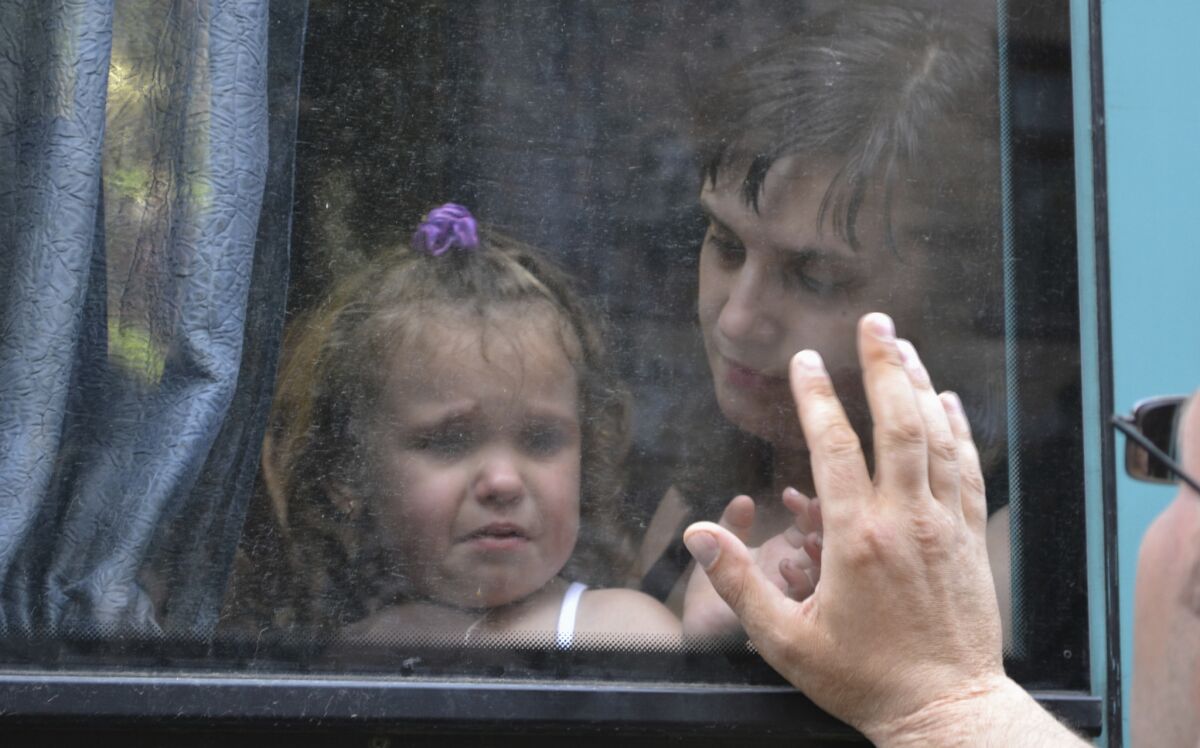 A young girl bids a tearful farewell as she waits aboard a bus to depart embattled Slovyansk in eastern Ukraine. Russia reports 30,000 have fled fighting in the area to take refuge in the Rostov region.