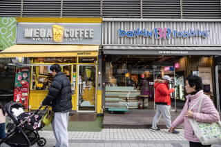 Pedestrians in Seoul walk past stores whose names are in English.