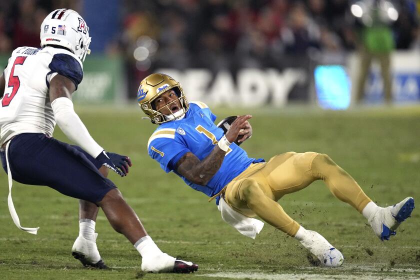 UCLA quarterback Dorian Thompson-Robinson, right, slips as he runs the ball while under pressure.