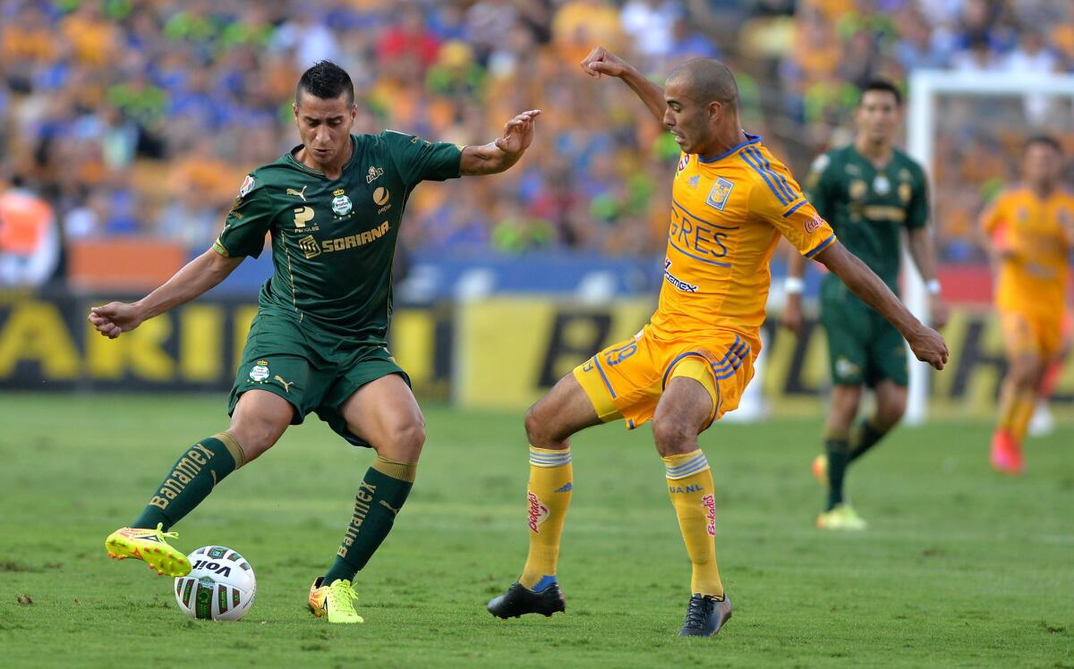 Guido Pizarro (der), de Tigres, pelea un balón a Diego González, del Santos.