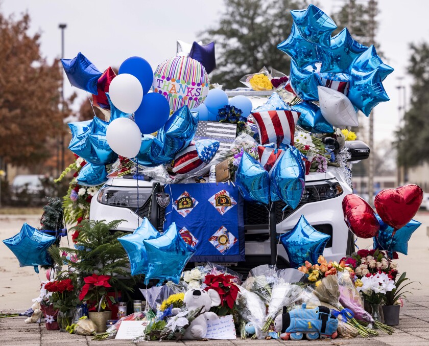 Balloons and flowers cover a patrol car at a memorial for a slain police officer at the Mesquite Police Department on Saturday, Dec. 4, 2021, in Mesquite, Texas. Police have released the name of the officer who was fatally shot while responding to a disturbance call outside a suburban Dallas supermarket. Mesquite police said Saturday that Officer Richard Houston was killed Friday. Police said a prayer vigil will be held for him Sunday, Dec. 5, 2021 in front of the police department. (Juan Figueroa/The Dallas Morning News via AP)