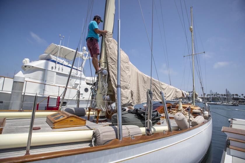 Long Beach, CA - July 14: Ben Wheatley, head rigger, Bahia Marine, who's family business can't find employees to work, wraps a cover on a sail onboard the Chubasco, a Sparkman & Stephens 67' sailboat built in 1939 in Alamitos Bay Marina in Long Beach and hasn't really had time off since the pandemic begun Wednesday, July 14, 2021. (Allen J. Schaben / Los Angeles Times)
