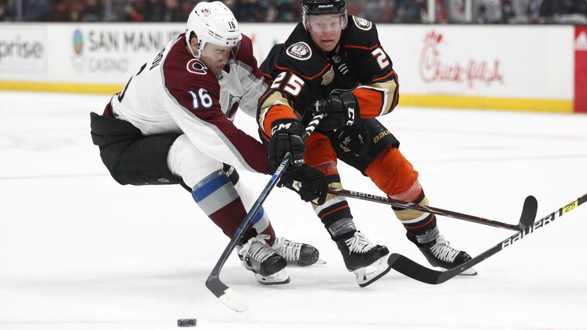 Ducks' Ondrej Kase reaches for the puck next to Colorado Avalanche's Nikita Zadorov during the second period on Sunday.