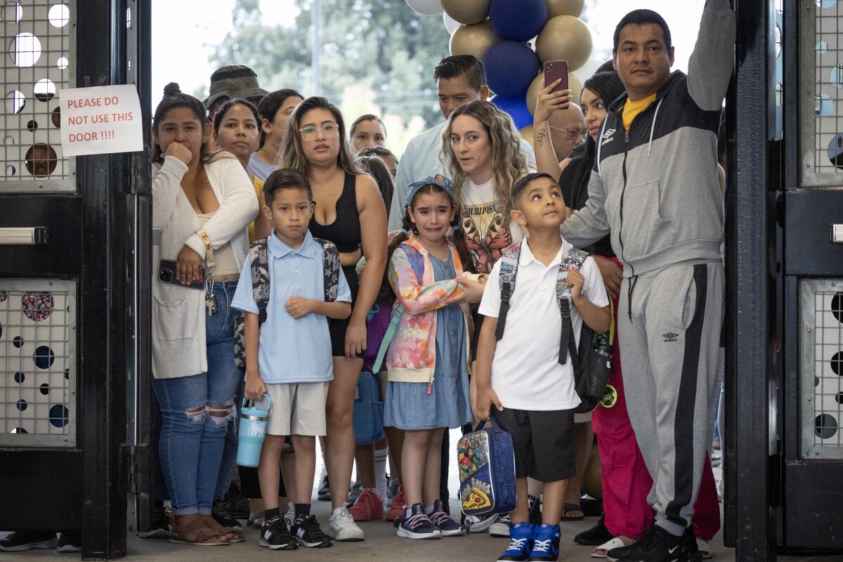 A group of parents and school children stand in a doorway.