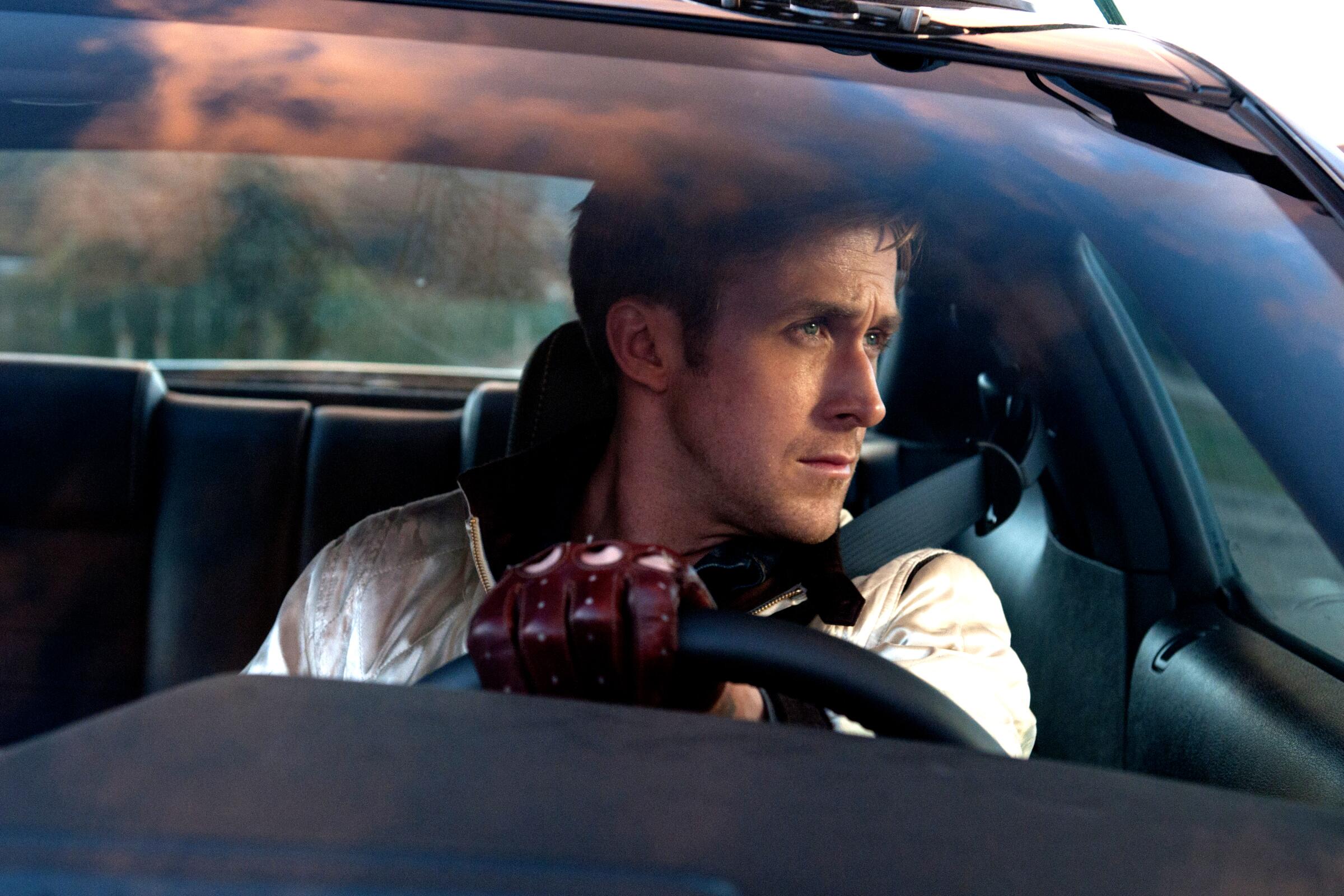 A man in a white jacket steers a car.