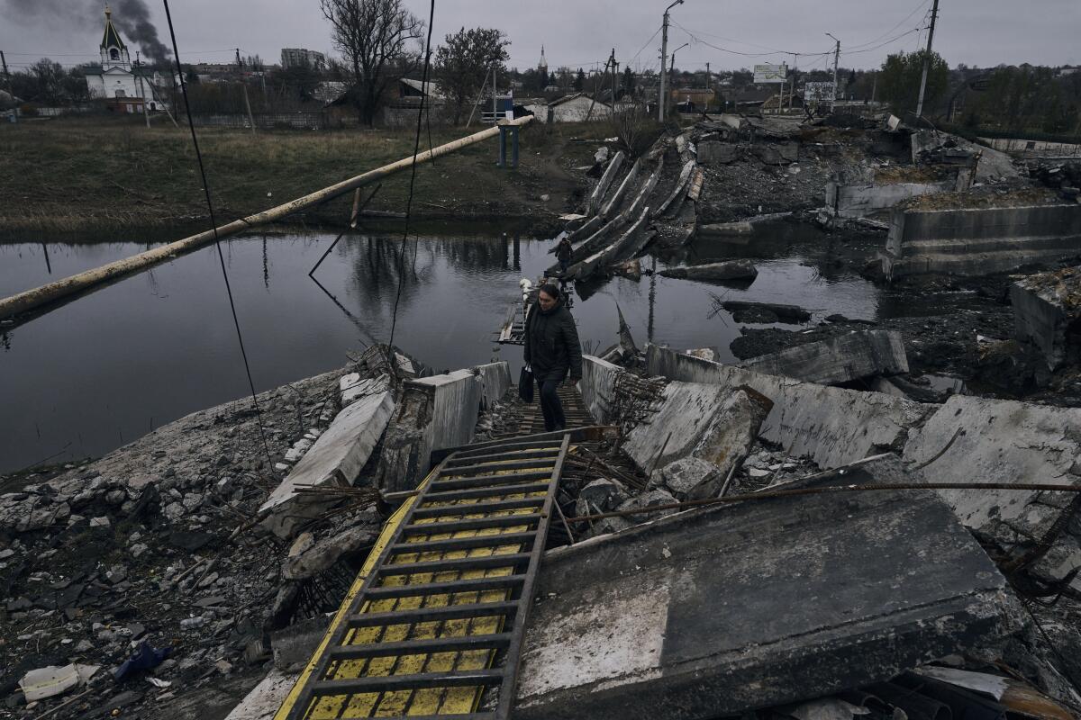 Una mujer camina por un puente destrozado en Bakhmut, Ucrania, el viernes 11 de noviembre de 2022.