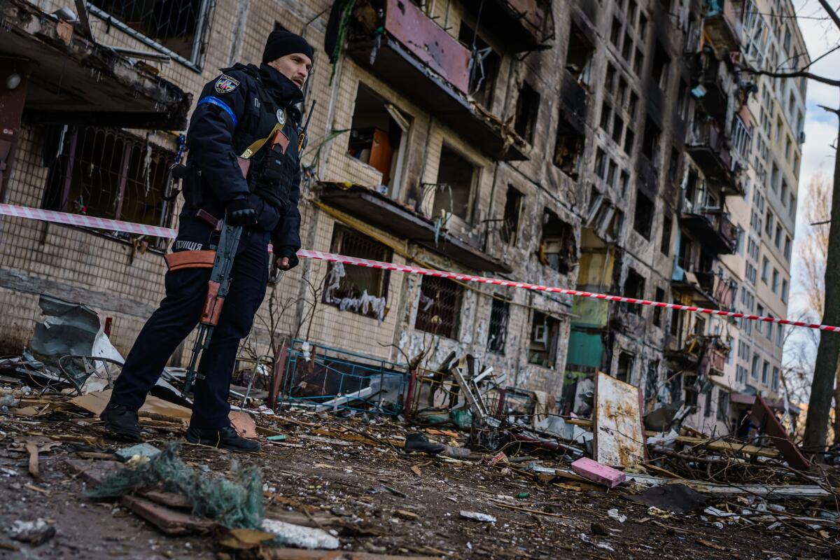 Man stands in front of an apartment building in Kyiv damaged by a Russian strike