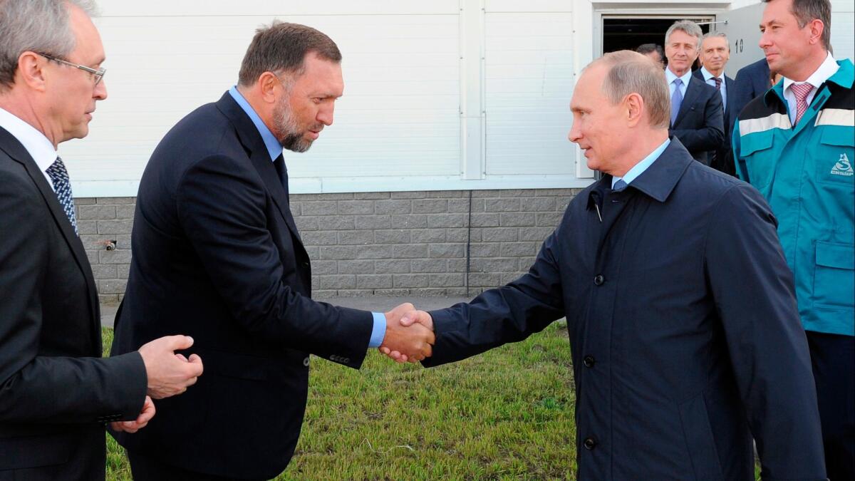 In this 2014 photo, Russian President Vladimir Putin, right, shakes hands with Russian metals magnate Oleg Deripaska while visiting the RusVinyl plant in Kstovo, in Russia's Nizhny Novgorod region. (Mikhail Klimentyev / Associated Press)