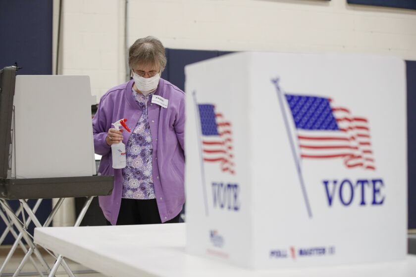 An election observer cleans voting booths during a Democratic presidential primary election at the Kenosha Bible Church gym in Kenosha, Wisconsin, on April 7, 2020. - Americans in Wisconsin began casting ballots Tuesday in a controversial presidential primary held despite a state-wide stay-at-home order and concern that the election could expose thousands of voters and poll workers to the coronavirus. Democratic officials had sought to postpone the election but were overruled by the top state court, and the US Supreme Court stepped in to bar an extension of voting by mail that would have allowed more people to cast ballots without going to polling stations. Both courts have conservative majorities. (Photo by KAMIL KRZACZYNSKI / AFP) (Photo by KAMIL KRZACZYNSKI/AFP via Getty Images)