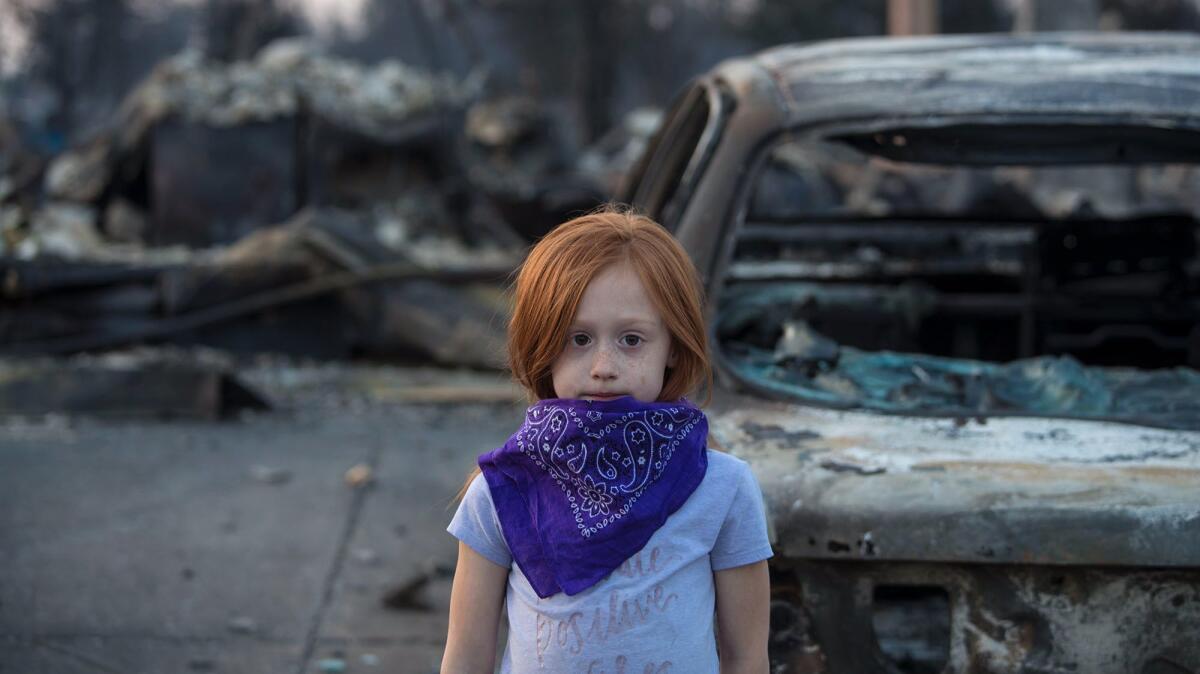 Chloe Hoskins, 7, tags along with her father, who was checking on a neighbor's burned out property in the Coffey Park neighborhood in Santa Rosa.