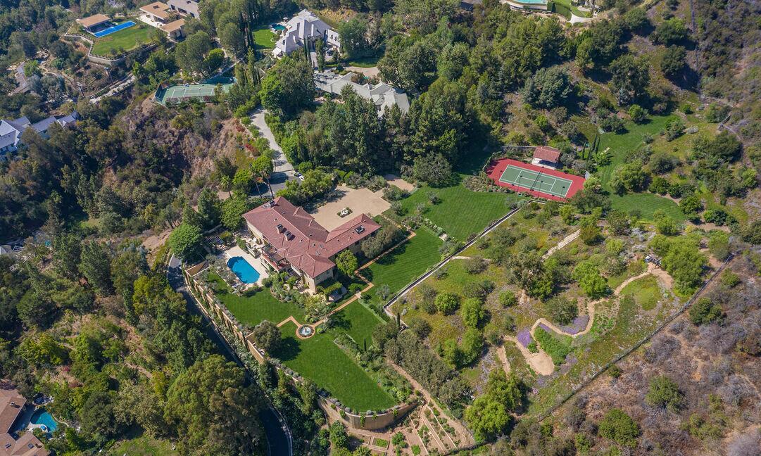 Aerial view of the estate with a house, pool, trees, lawn and shrubs.